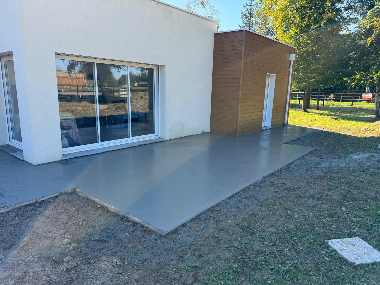 Dalle en béton fraîchement coulée pour une terrasse extérieure.